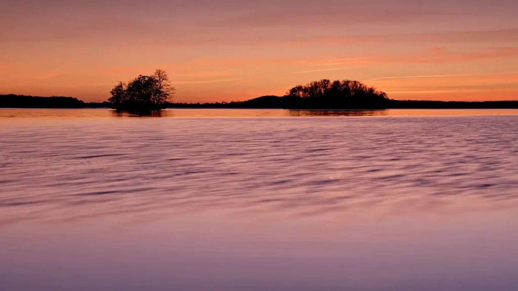 lange brennweite zur aufnahme zweier inseln in einem see zum farbenfrohen sonnenuntergang