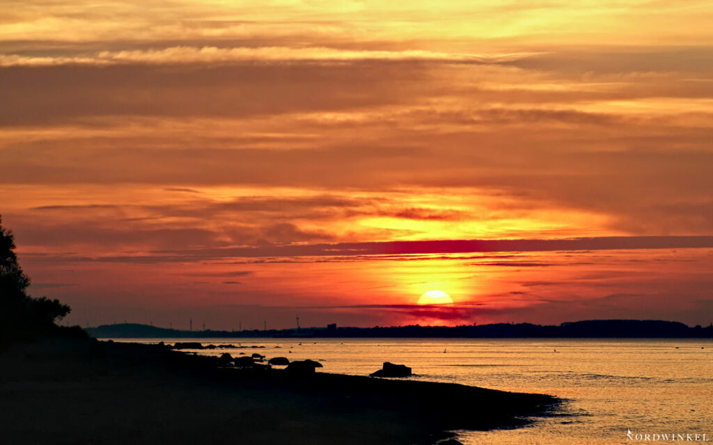 sonnenuntergang mit scheerenschnittsilhouette eines Strandes im vordergrund