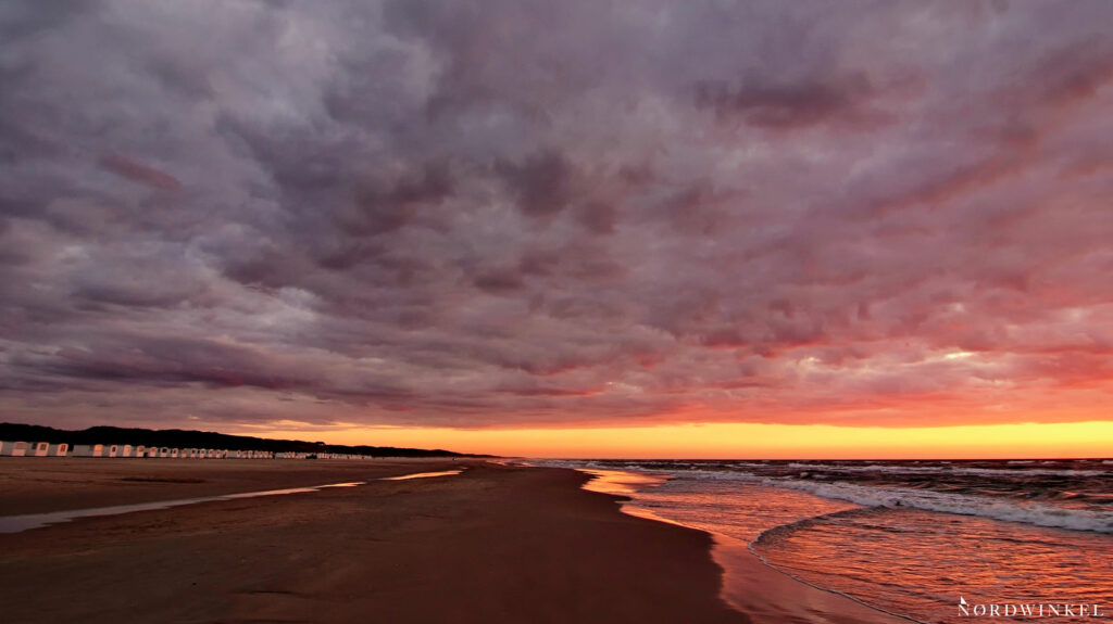 sonnenuntergang am strand unter drohender gewitterwolkenwand