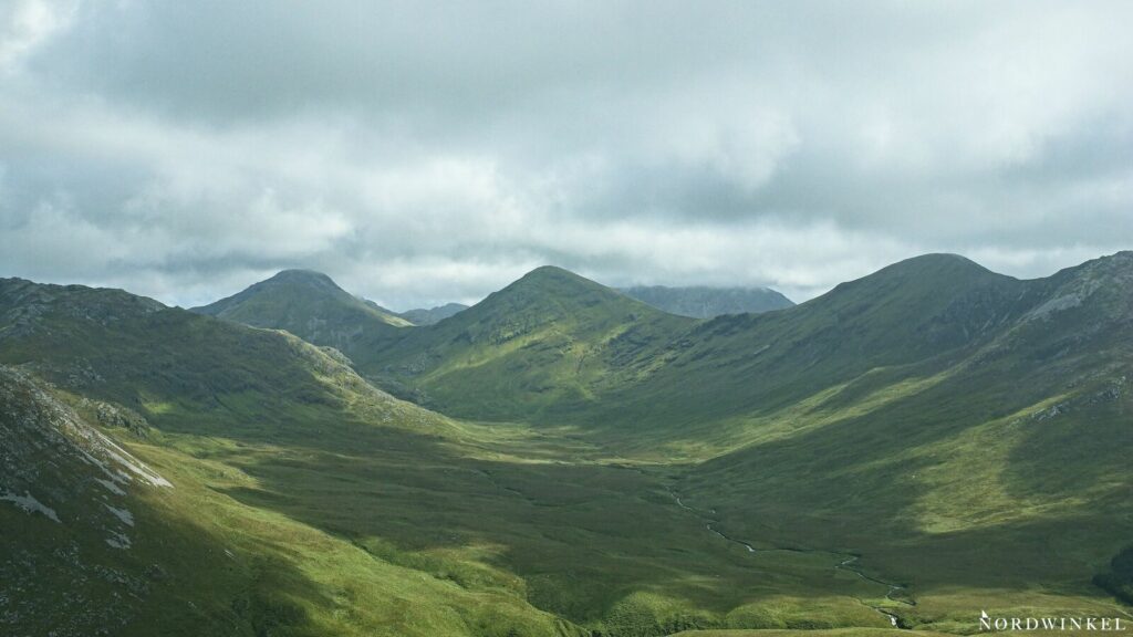 grüne hänge an bergen unter grauem himmel in irland