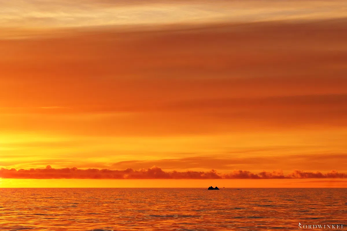 sonnenuntergangsstimmung mit gelbem himmel auf dem meer und einem kleinen eisberg