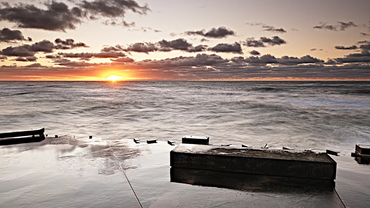 stürmische nordsee zum sonnenuntergang an einem anleger