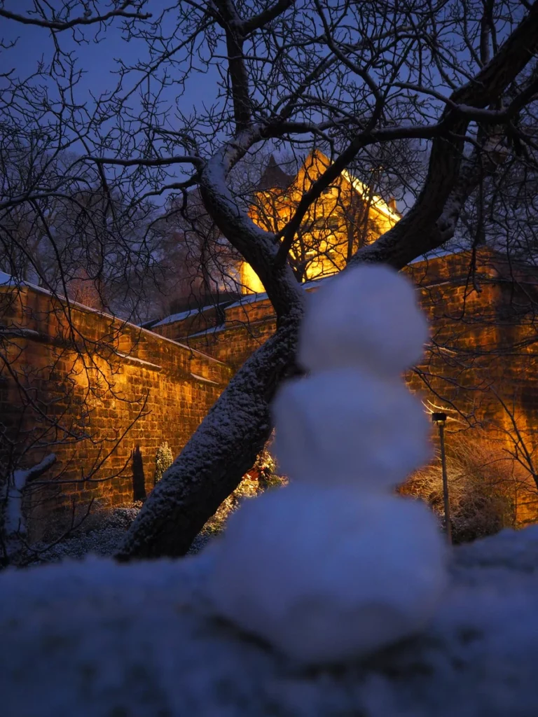 schnee an einem winterabend vor erleuchteten gebäude