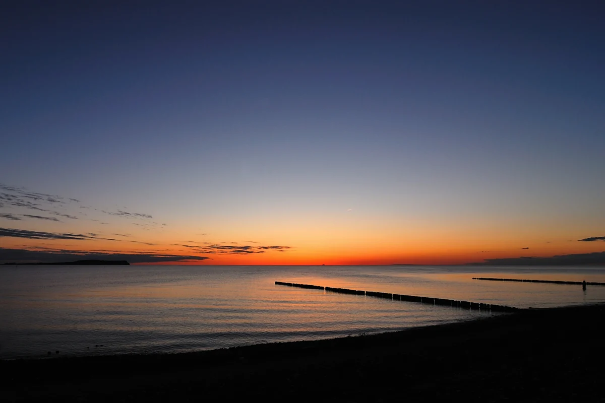 buhnen zum sonnenuntergang an einem steinstrand