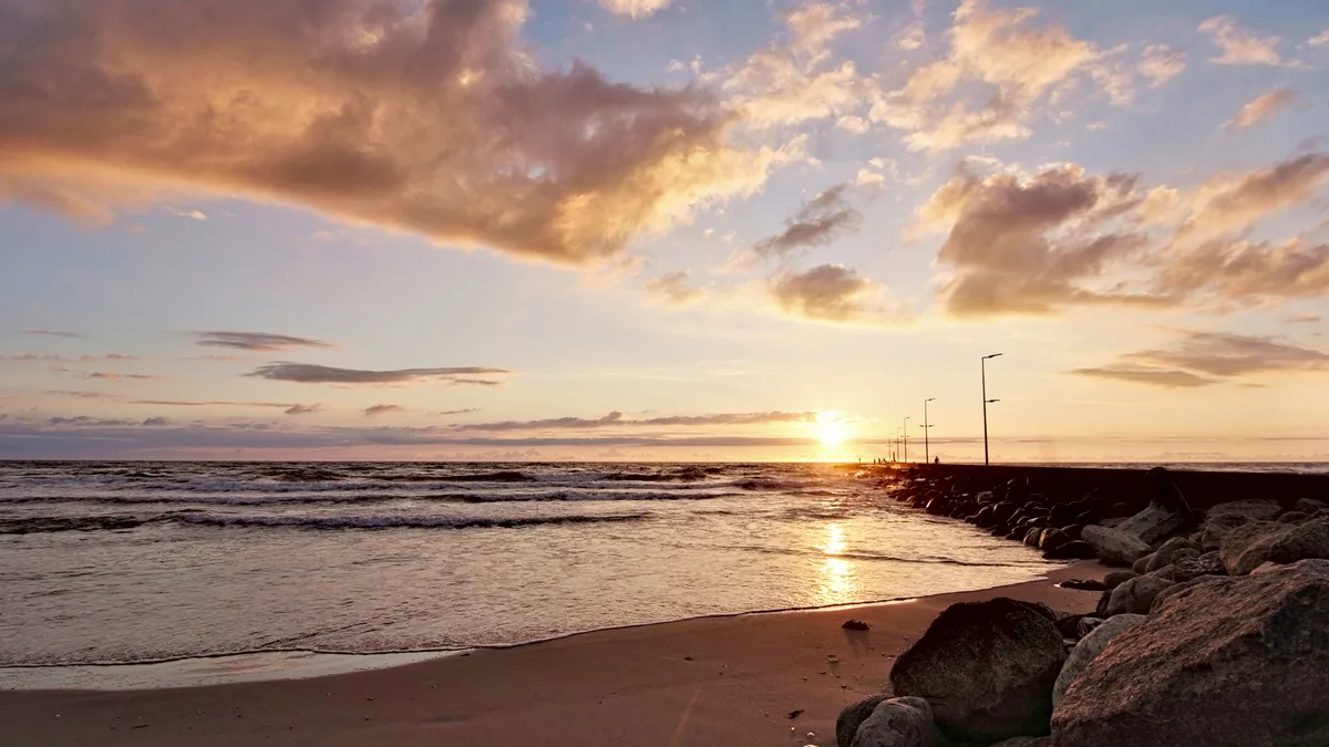 sonnenuntergang im goldenen schnitt am strand mit einer mole